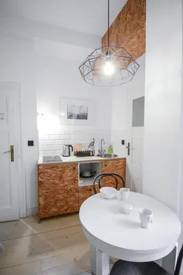 a white kitchen with a white table in a room at LION apartments - Gold in Kraków