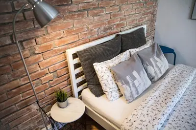 a brick wall with a bench with pillows and a lamp at LION apartments - Gold in Kraków