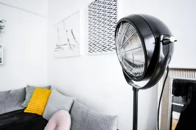 a fan in a living room next to a couch at LION apartments - Gold in Kraków