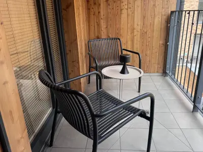 a bedroom with a bed and a chair and windows at InPoint Krakow Suites - Steps from Main Station&Old Town Self Check-in in Kraków