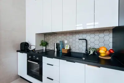 a kitchen with white cabinets and a black counter top at City Lights Topolowa 8 in Kraków