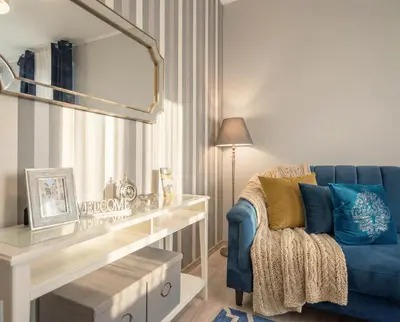 a living room with a blue chair and a mirror at City Lights Topolowa 8 in Kraków