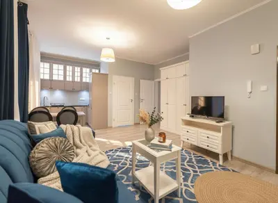 a living room with a blue couch and a tv at City Lights Topolowa 8 in Kraków