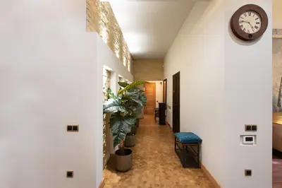 a hallway with white walls and a clock on the wall at Krakowhomes in Kraków