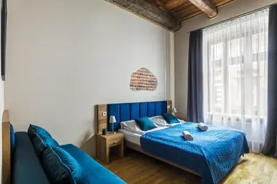 a bedroom with a blue bed and a couch at Aparthotel Pergamin in Kraków