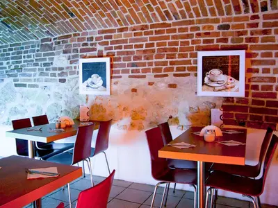 a restaurant with tables and chairs and a brick wall at Aparthotel Pergamin in Kraków