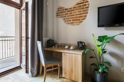 a room with a desk with a chair and a television at Aparthotel Pergamin in Kraków