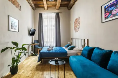 a living room with a blue couch and a bed at Aparthotel Pergamin in Kraków