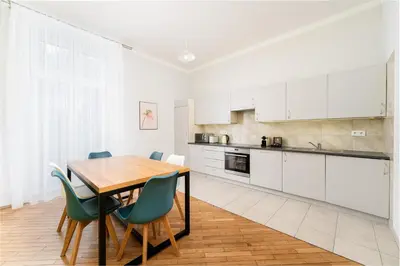 a kitchen with white cabinets and a wooden table and chairs at 1898 Parkside Boutique Residence in Kraków