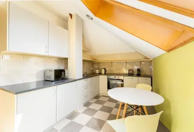 a kitchen with white cabinets and a table and chairs at 1898 Parkside Boutique Residence in Kraków