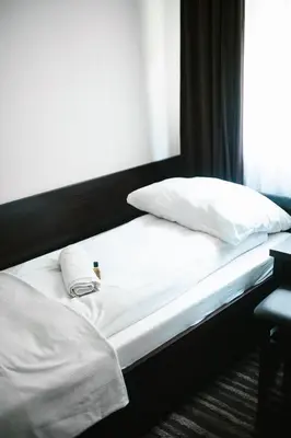 a bed with white sheets and pillows on it at Willa Zacisze - Apartament dwupoziomowy in Kalwaria Zebrzydowska