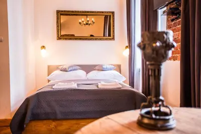 a bedroom with a bed with a mirror on the wall at Lovenovsky Apartments in Kraków