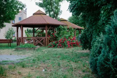 a wooden gazebo in a park with flowers at Pałac Koronny Noclegi & Wypoczynek in Wodzisław