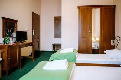 a room with two beds and a desk and a television at Pałac Koronny Noclegi & Wypoczynek in Wodzisław