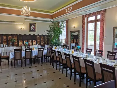 a dining room with tables and chairs and a chandelier at Pałac Koronny Noclegi & Wypoczynek in Wodzisław