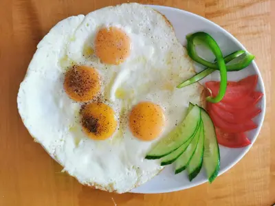a white plate with eggs and vegetables on a table at Pałac Koronny Noclegi & Wypoczynek in Wodzisław