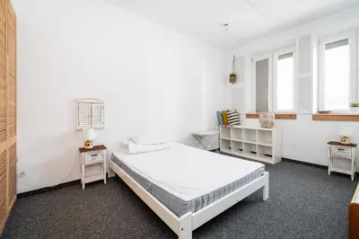 a white room with a bed and two windows at Master Corner Apartment in Kraków