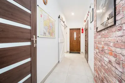 a corridor with a brick wall and a door at Master Corner Apartment in Kraków