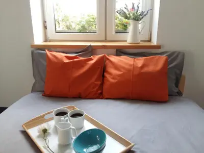 a tray with two cups on a bed with orange pillows at Master Corner Apartment in Kraków