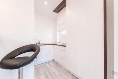 a kitchen with white cabinets and a black chair at BAKO Apartments in Skawina