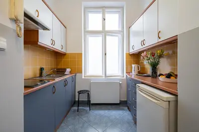 a kitchen with white cabinets and a window at Kazimierz Pearl Apartments in Kraków