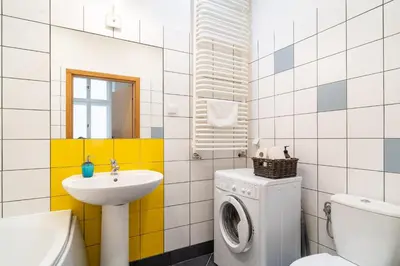 a bathroom with a washing machine and a sink at Kazimierz Pearl Apartments in Kraków