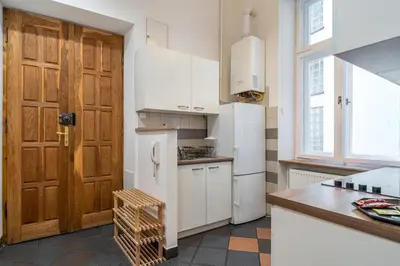 a kitchen with white appliances and a wooden door at Kazimierz Pearl Apartments in Kraków