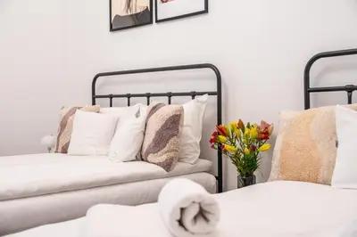 a living room with two beds with pillows and flowers at Kazimierz Pearl Apartments in Kraków