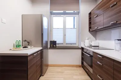a kitchen with wooden cabinets and a large window at PlayHouse Apartments in Kraków
