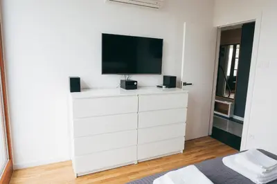 a white dresser with a television on top of it at Grey Apartment Kołowa in Kraków