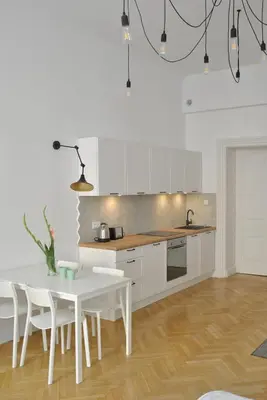 a kitchen with a white table and white cabinets at Florianska Apartment in Kraków