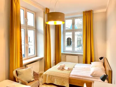 a bedroom with yellow curtains and a bed and a chair at FAUST Apartments in the Heart of KAZIMIERZ by MINT APARTMENT in Kraków