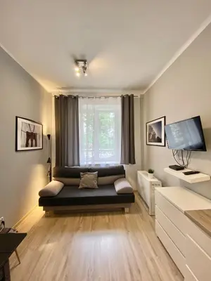 a living room with a couch in front of a window at Friendhouse Apartments Avenue in Kraków