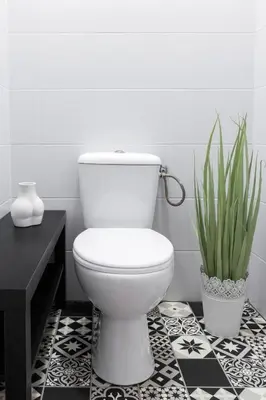 a bathroom with a white toilet and a black and white floor at Friendhouse Apartments Avenue in Kraków