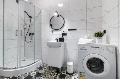 a bathroom with a washing machine and a shower at Friendhouse Apartments Avenue in Kraków