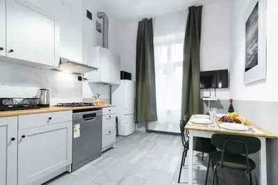 a kitchen with white cabinets and a table with chairs at Friendhouse Apartments Avenue in Kraków