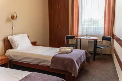 a hotel room with a bed and a table and chairs at Pastoral Lodge at the Sanctuary of the Divine Mercy in Kraków