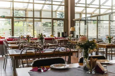 a dining room with tables and chairs and windows at Pastoral Lodge at the Sanctuary of the Divine Mercy in Kraków