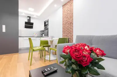 a living room with a couch with a vase of red roses at CityHeaven with parking and AC in Kraków