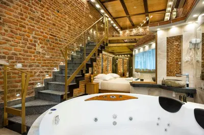 a bathroom with a bath tub in a room with a brick wall at Aparthotel Stare Miasto in Kraków