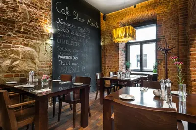 a dining room with tables and chairs and a chalkboard at Aparthotel Stare Miasto in Kraków