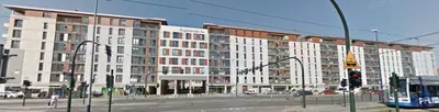 a large white building on a city street with a bus at Cracow Stay Apartments in Kraków