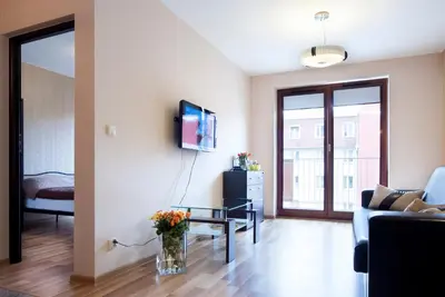a living room with a couch and a tv on a wall at Cracow Stay Apartments in Kraków