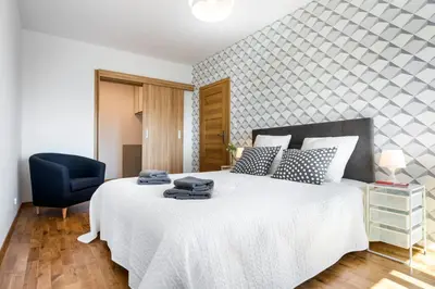 a bedroom with a white bed and a blue chair at JT Apartments/Dworska in Kraków