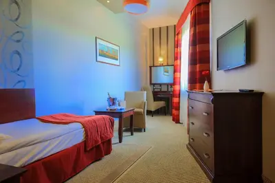 a hotel room with a bedroom with a bed and a desk at Hotel Galicja Superior Wellness & Spa in Oświęcim