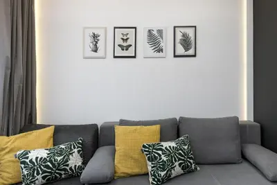 a living room with a gray couch with four pictures on the wall at Słowackiego 11B - cozy studio by Homeprime in Kraków
