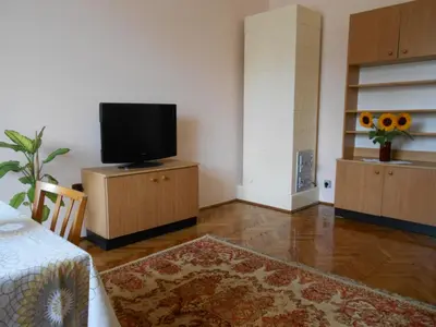 a living room with a tv on a cabinet and a table at Apartament Krakowski Styl in Kraków