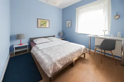 a blue bedroom with a bed and a desk and a window at Bed&Breakfast Mikunda in Chrzanów