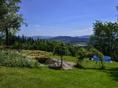 a wooden bridge in a field with trees and mountains at domek simonka zawoja in Zawoja
