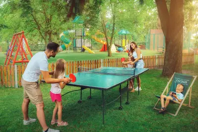 a man and children playing ping pong in a park at Zacisze Nad Nidą Resort in Pińczów